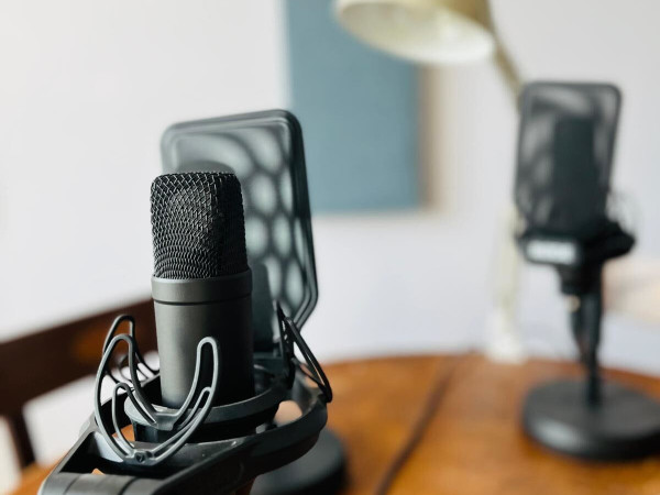 Photograph of three microphones and a lamp on a desk.